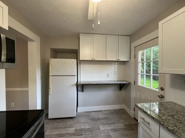 a kitchen with granite countertop a refrigerator a stove a microwave and island