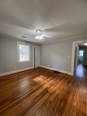 a view of an empty room with wooden floor and a window