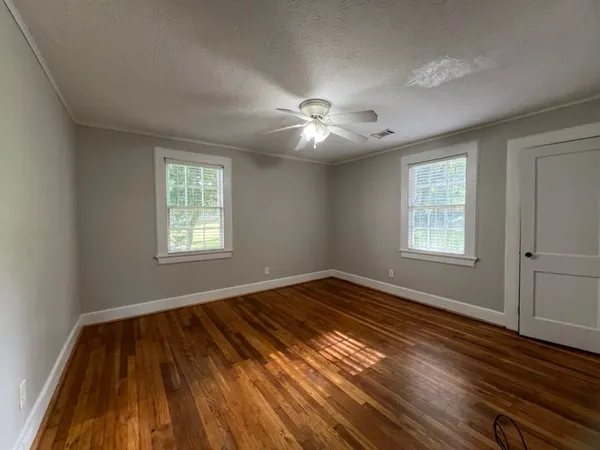 a view of empty room with wooden floor and fan