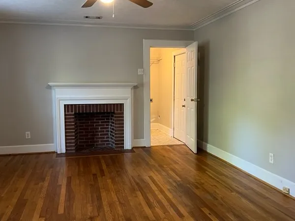 an empty room with wooden floor fireplace and windows