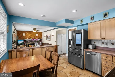 a kitchen with stainless steel appliances granite countertop a stove refrigerator dining table and chairs