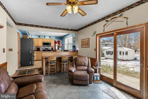 a living room with furniture a ceiling fan and a large window