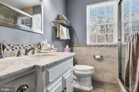 a bathroom with a granite countertop sink a toilet and a mirror
