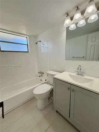 a bathroom with a toilet a sink a tub and a mirror