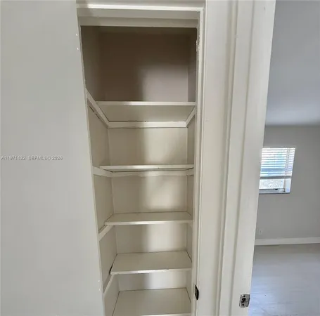 a walk in closet with wooden floor