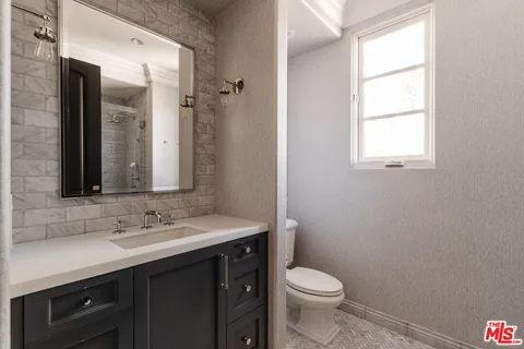 a bathroom with a sink a toilet a window and a mirror