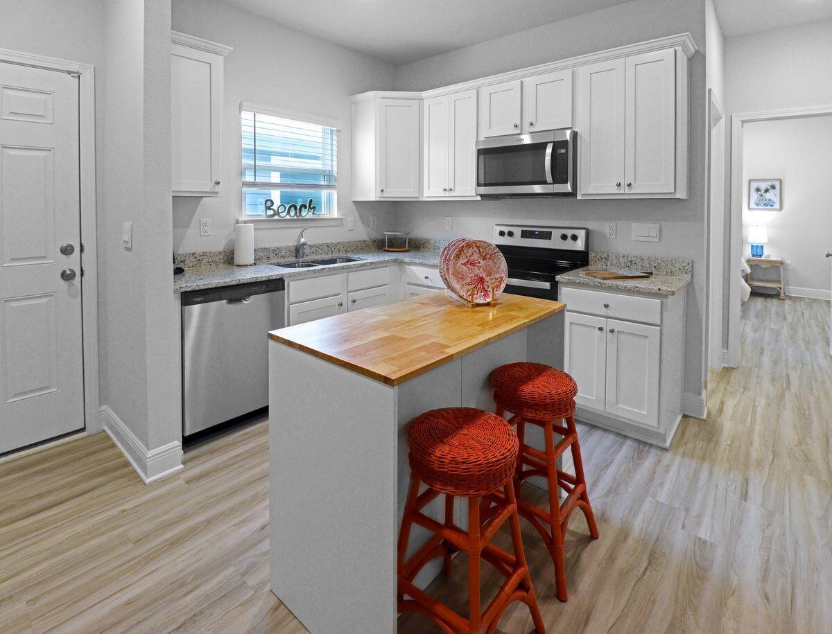 769 Backwater Road Port St. Joe, FL 32456 - Photo 25 of 45 a kitchen with stainless steel appliances granite countertop white cabinets a stove a sink and a wooden floor