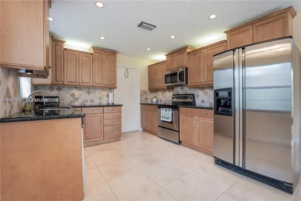 a kitchen with stainless steel appliances granite countertop a refrigerator and a stove top oven