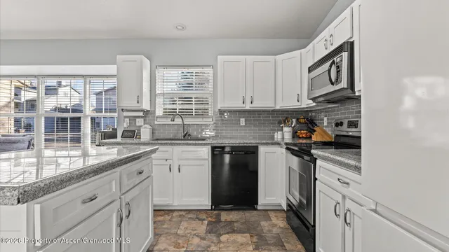 a kitchen with granite countertop white cabinets and white appliances