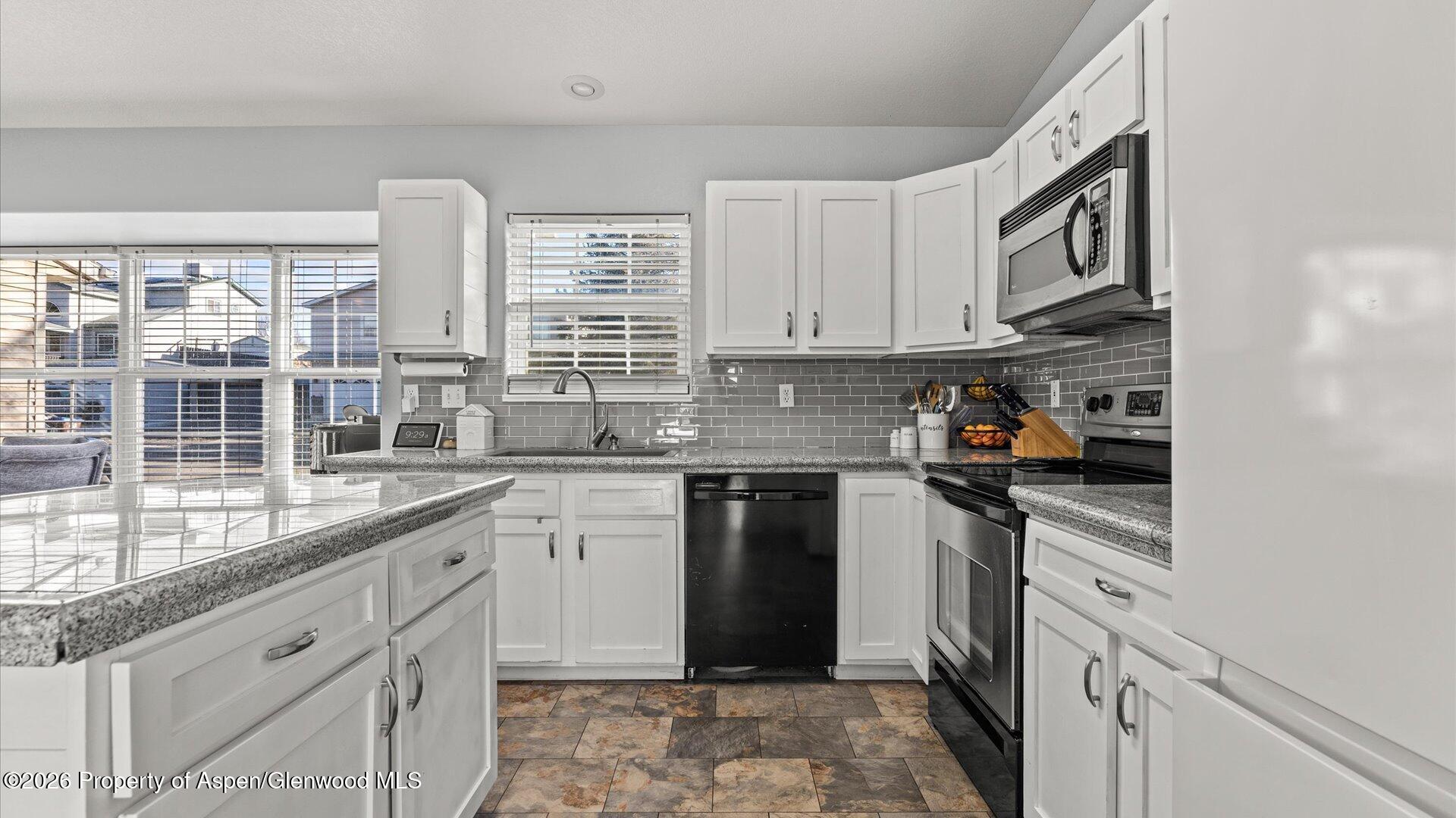 1557 East 12th Street Rifle, CO 81650 - Photo 12 of 26 a kitchen with granite countertop white cabinets and white appliances