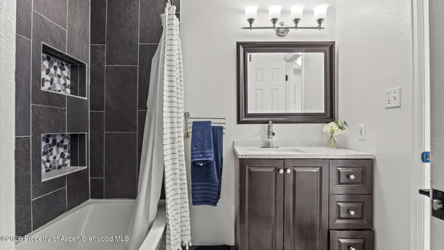 a bathroom with a granite countertop sink a mirror and shower