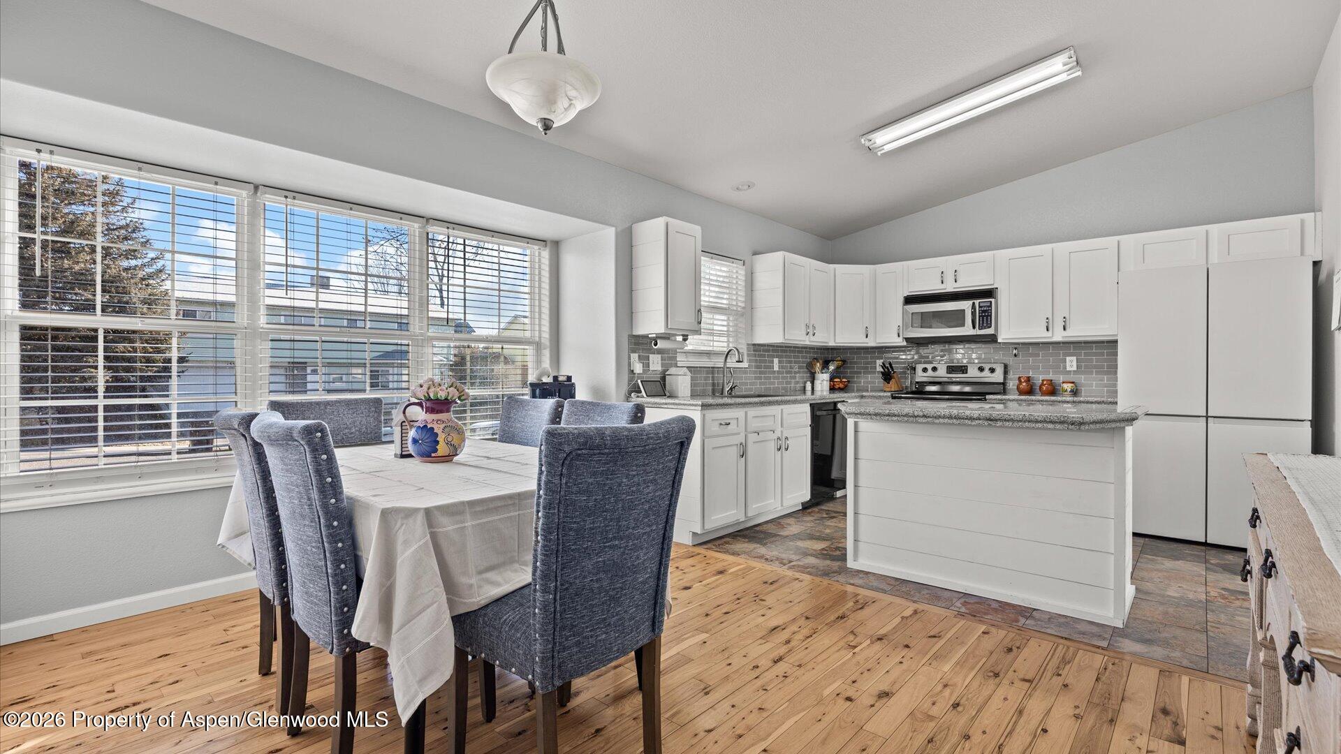 1557 East 12th Street Rifle, CO 81650 - Photo 8 of 26 a kitchen with stainless steel appliances granite countertop a stove a refrigerator a sink dishwasher a dining table and chairs with wooden floor
