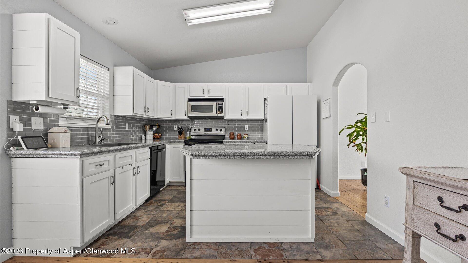 1557 East 12th Street Rifle, CO 81650 - Photo 10 of 26 a kitchen with kitchen island granite countertop a stove a sink a refrigerator a window a counter space and cabinets