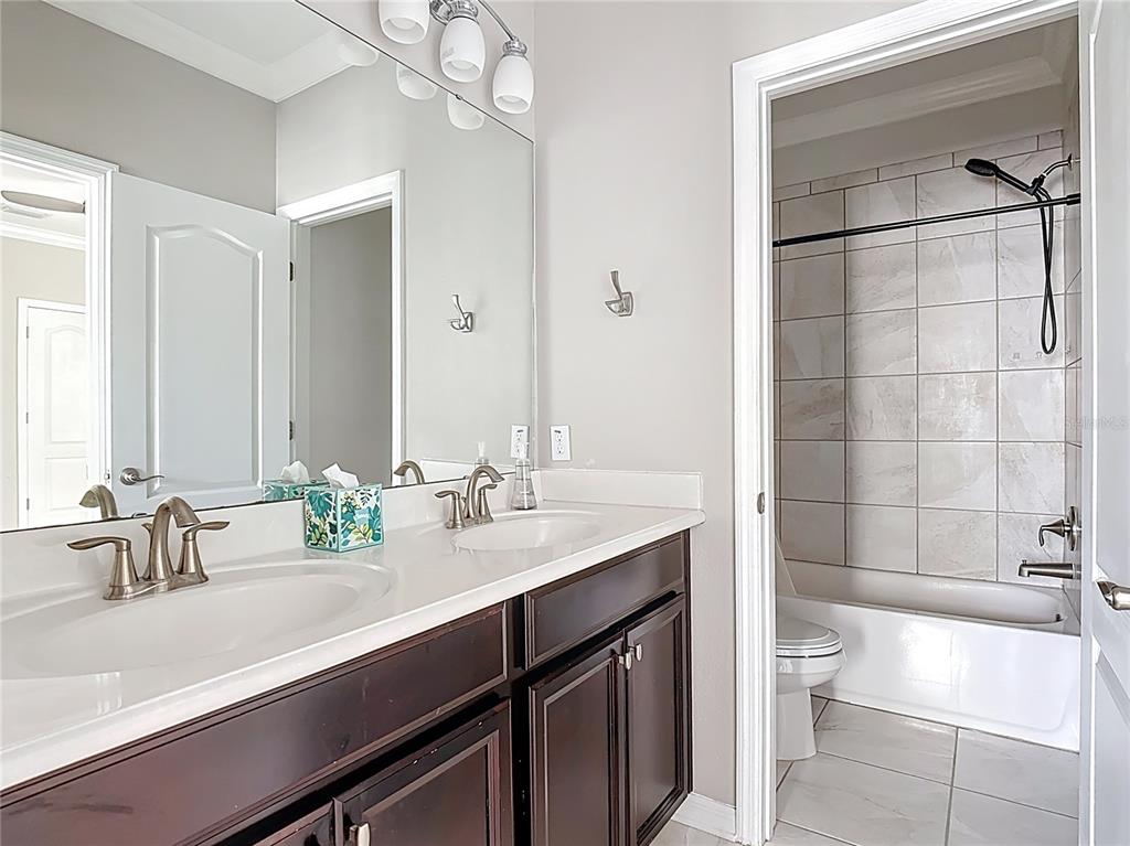 1513 Resolute Street Celebration, FL 34747 - Photo 37 of 43 a bathroom with a double vanity sink toilet and shower