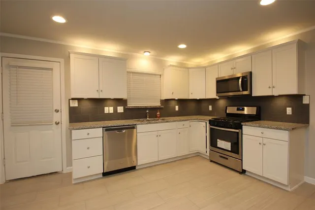 a kitchen with granite countertop white cabinets and stainless steel appliances