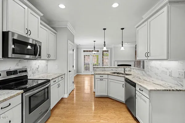 a kitchen with stainless steel appliances granite countertop a sink stove microwave and refrigerator
