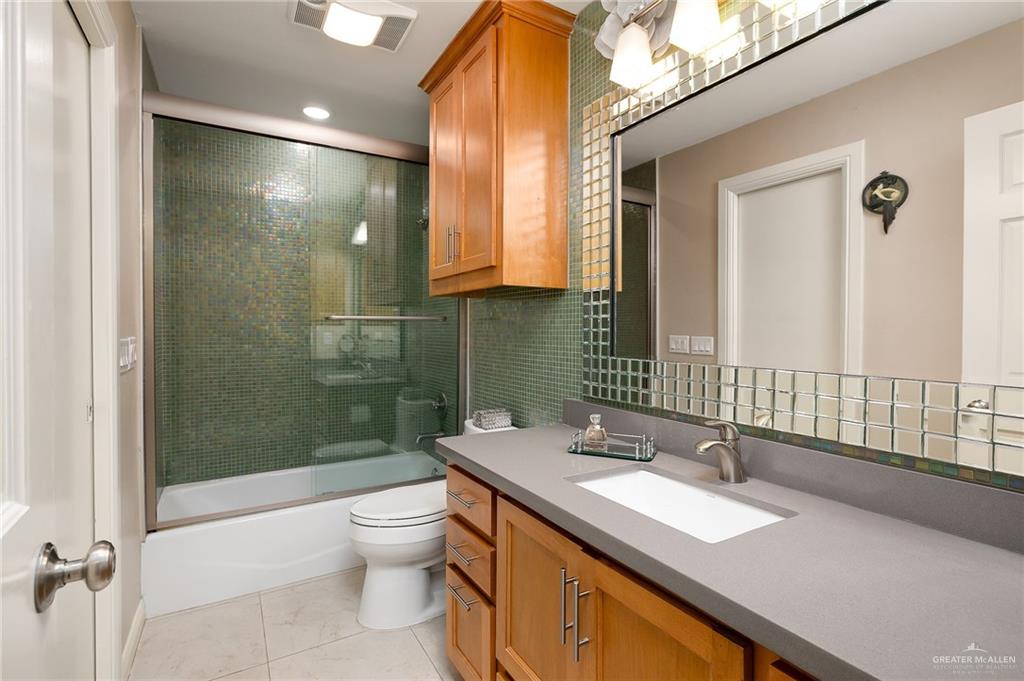 301 Vermont Avenue McAllen, TX 78503 - Photo 14 of 25 a bathroom with a granite countertop sink a toilet a mirror and shower