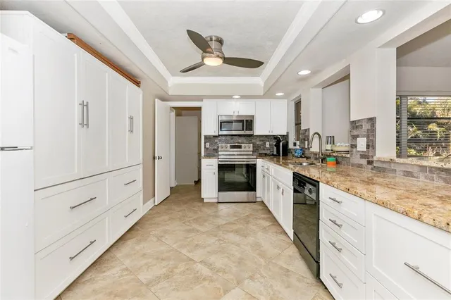 a large white kitchen with a stove a sink dishwasher and white cabinets with wooden floor