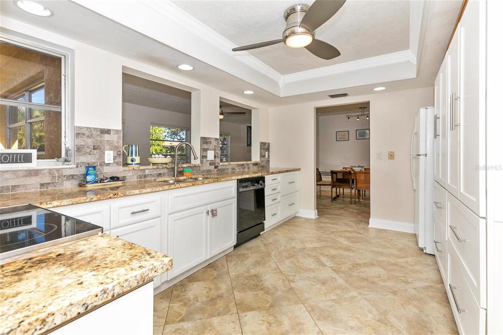 3039 Chase Circle Sarasota, FL 34231 - Photo 25 of 55 a large white kitchen with a stove a sink dishwasher and white cabinets with wooden floor