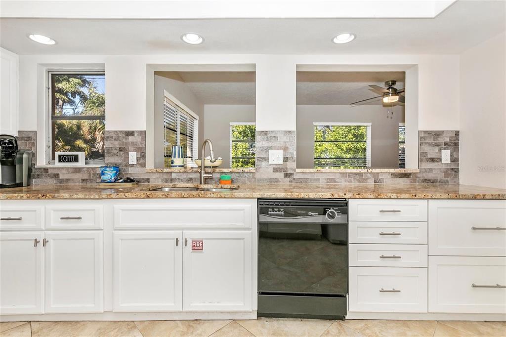 3039 Chase Circle Sarasota, FL 34231 - Photo 26 of 55 a kitchen with granite countertop a sink white cabinets and glass space