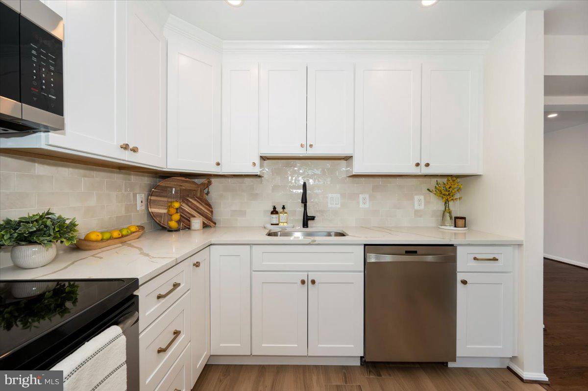 12144 Turnstone Court, Unit 87 Silver Spring, MD 20904 - Photo 14 of 56 a kitchen with white cabinets and a stove with wooden floor