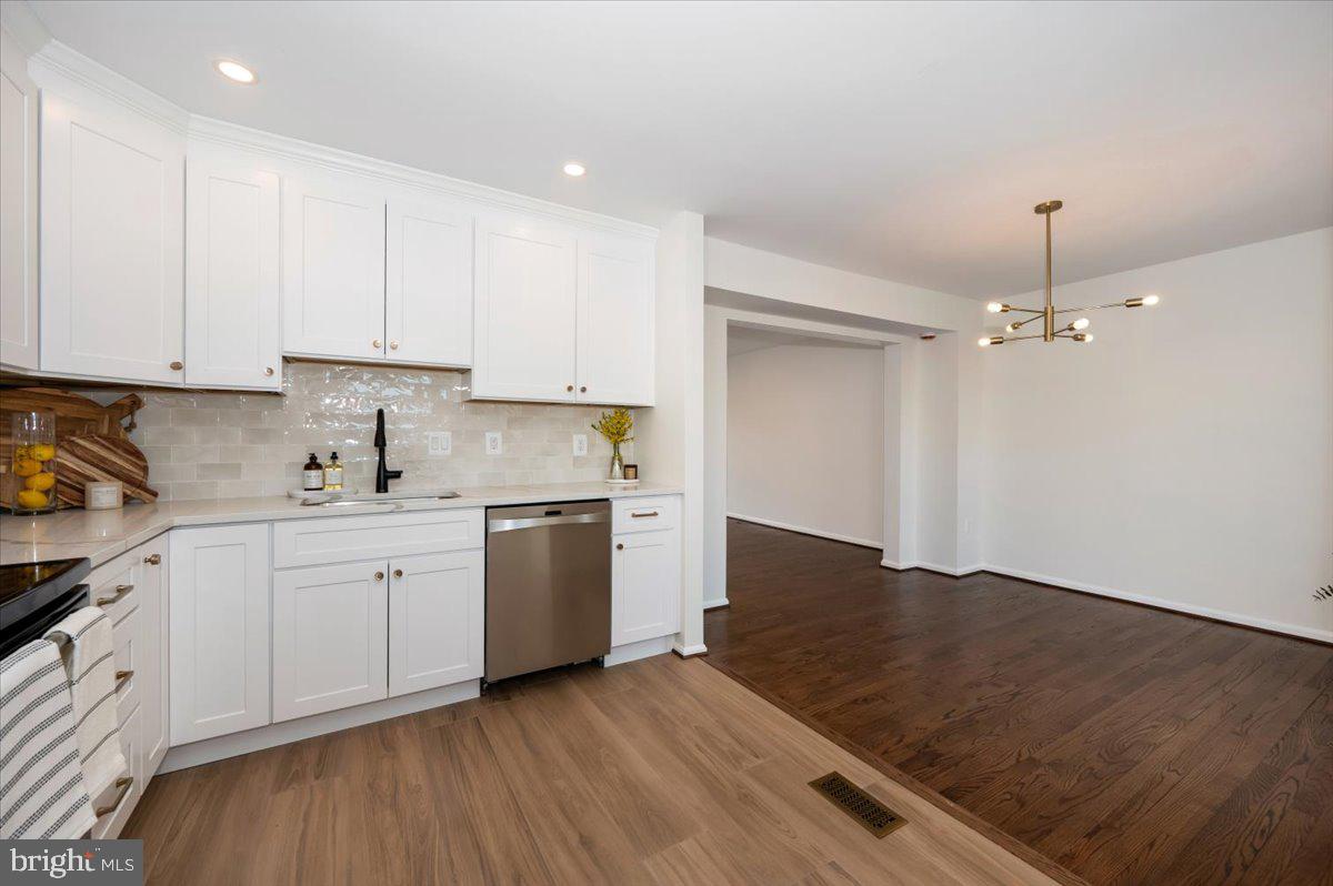 12144 Turnstone Court, Unit 87 Silver Spring, MD 20904 - Photo 16 of 56 a kitchen with granite countertop a stove a sink and white cabinets with wooden floor