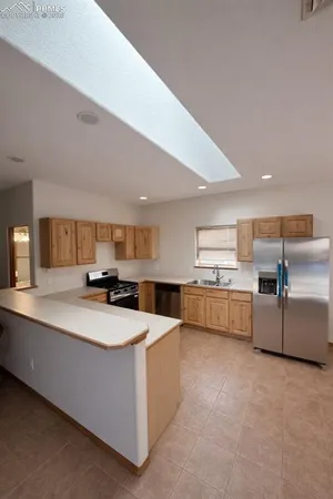 a kitchen with stainless steel appliances a sink a stove a refrigerator a white building and white cabinets