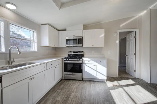 a kitchen with granite countertop a sink cabinets and stainless steel appliances