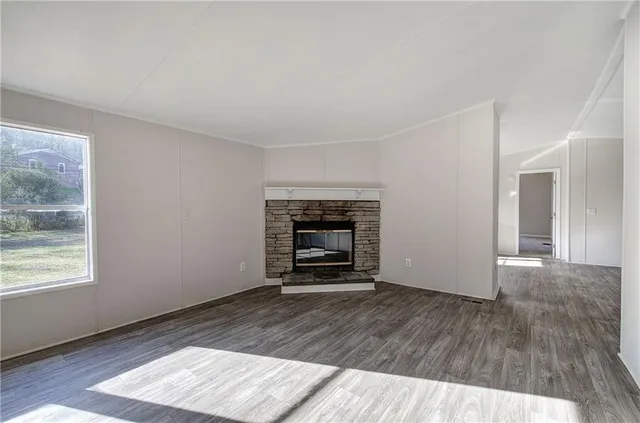 a view of an empty room with wooden floor fireplace and a window