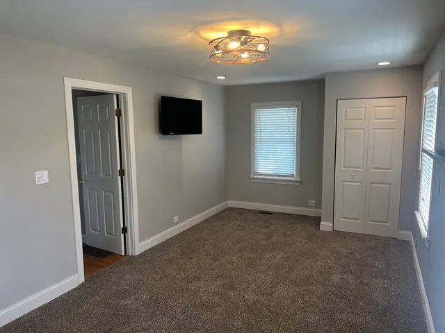 an empty room with windows closet and chandelier