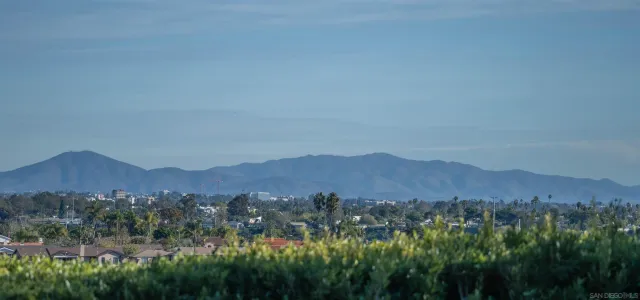 a view of a lush green field with mountains in the background
