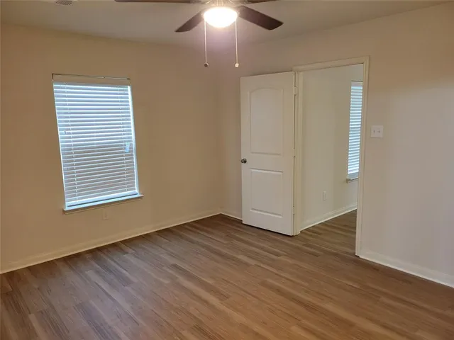 an empty room with wooden floor cabinet and windows
