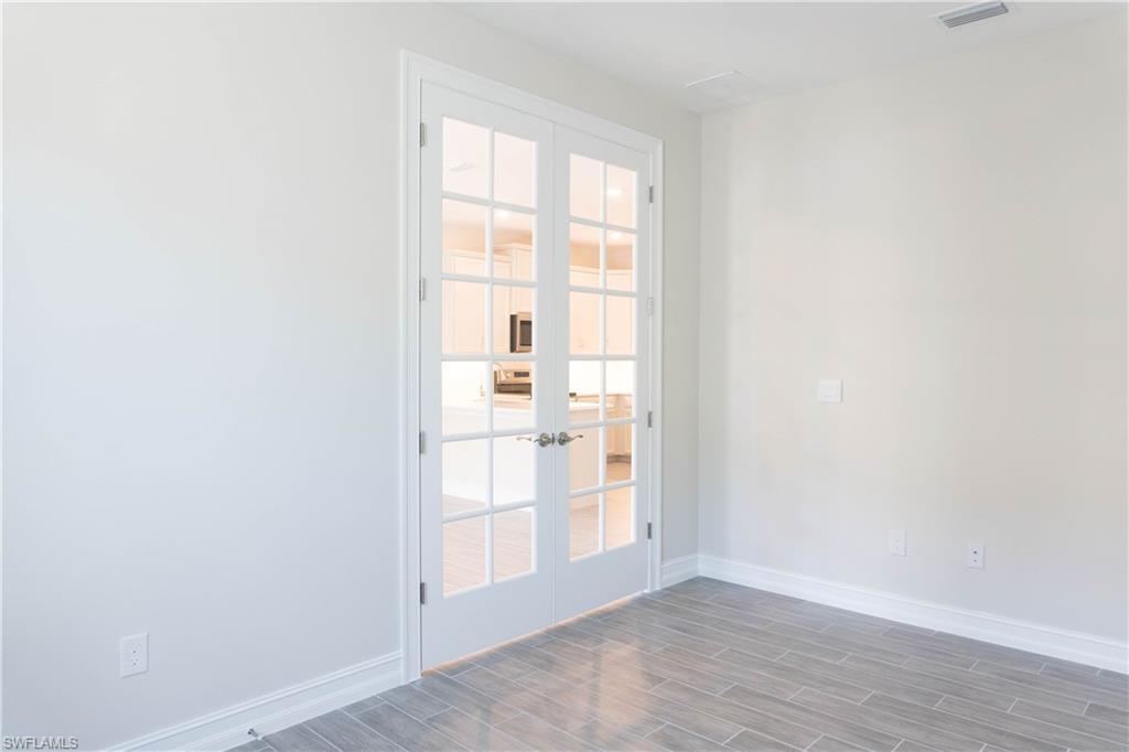 1050 Enbrook Loop Naples, FL 34114 - Photo 12 of 29 an empty room with wooden floor and windows