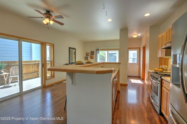 a kitchen with stainless steel appliances granite countertop a refrigerator a stove a sink dishwasher and a dining table with wooden floor