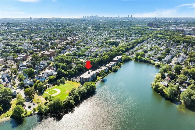 an aerial view of a city with lots of residential buildings lake and mountain view in back