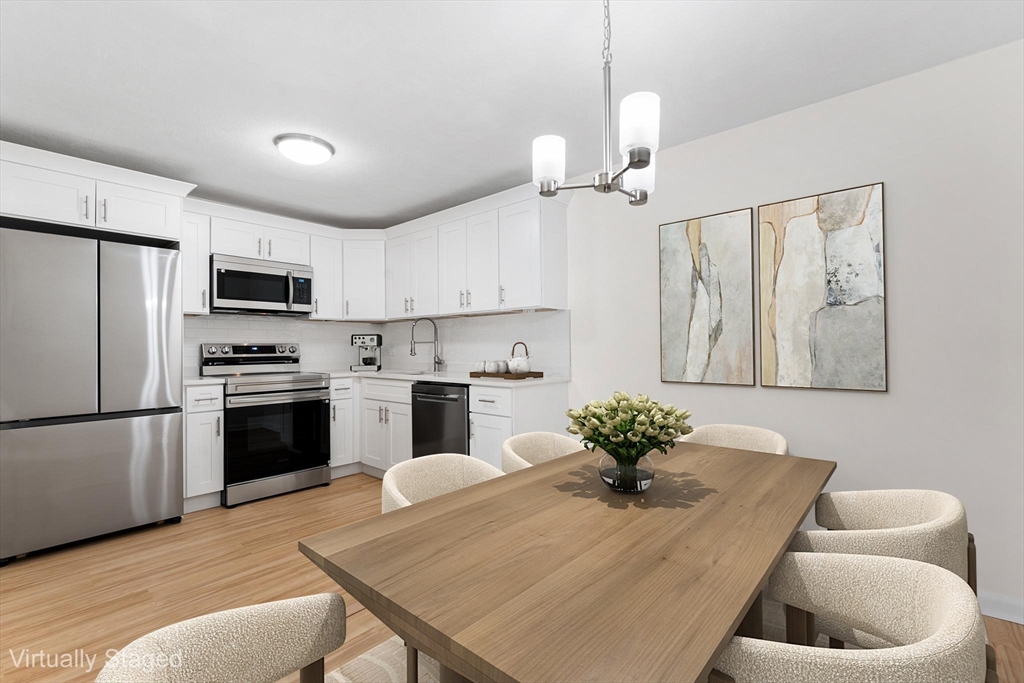 34 Hamilton Road, Unit 302 Arlington, MA 02474 - Photo 5 of 30 a kitchen with stainless steel appliances granite countertop a refrigerator a stove a sink dishwasher a dining table and chairs with wooden floor