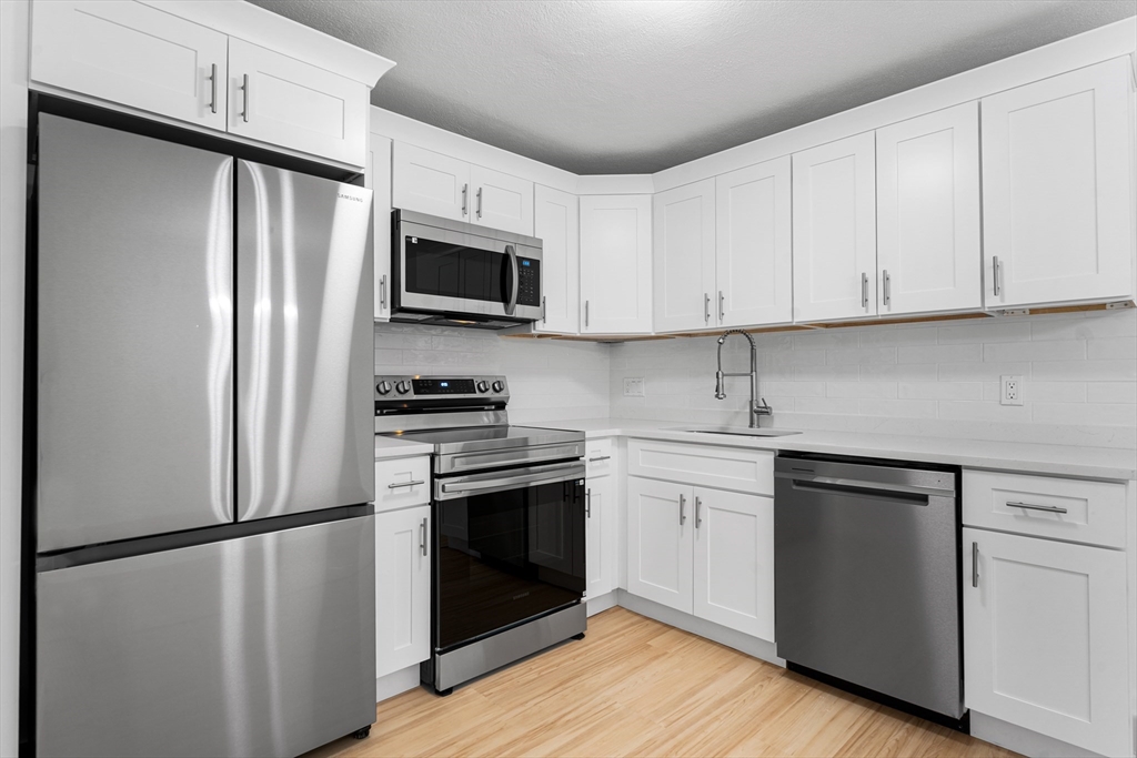 34 Hamilton Road, Unit 302 Arlington, MA 02474 - Photo 6 of 30 a kitchen with a refrigerator stove and white cabinets