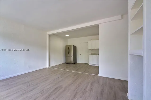 a view of an empty room with wooden floor and a window
