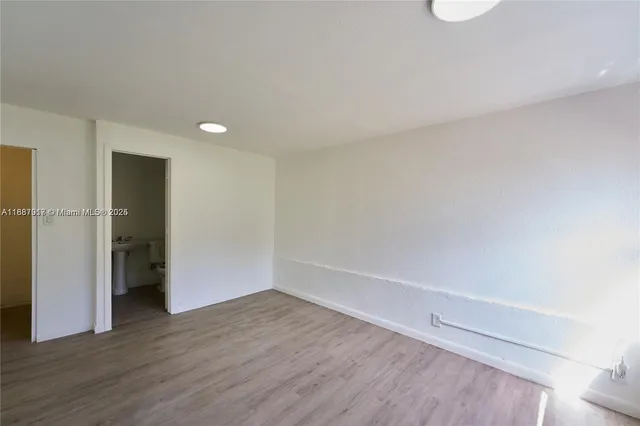 a view of an empty room with wooden floor and closet