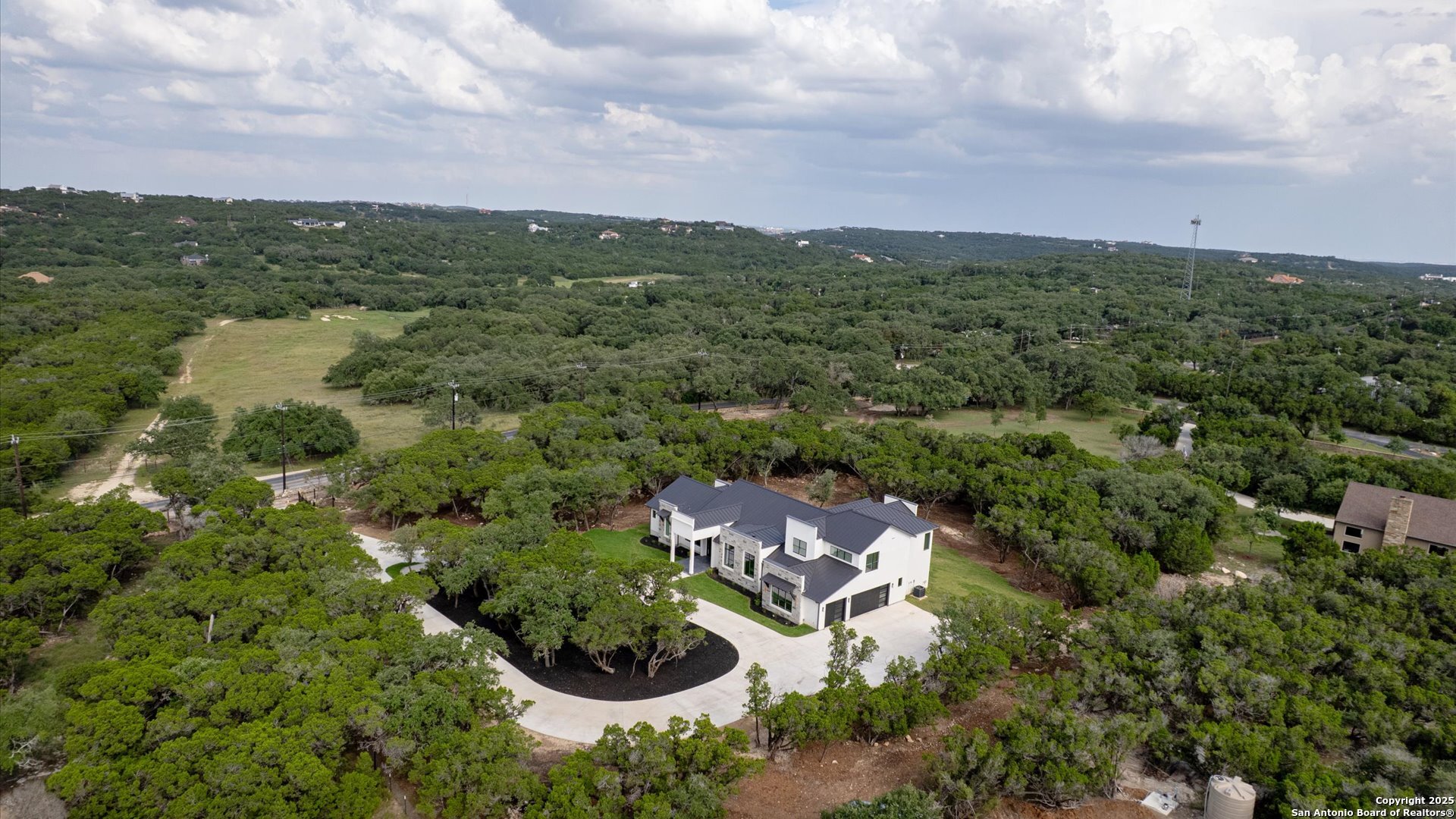 an aerial view of residential house with outdoor space and trees in the background