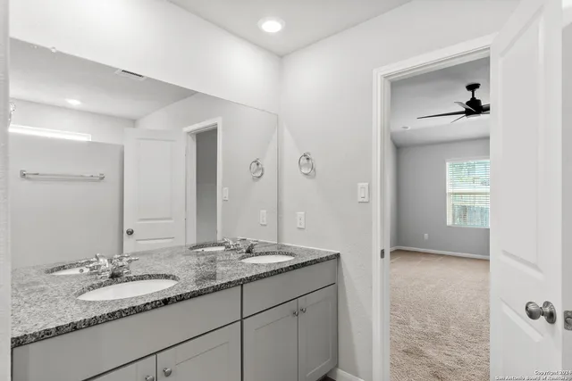 a bathroom with a granite countertop double vanity sink and mirror