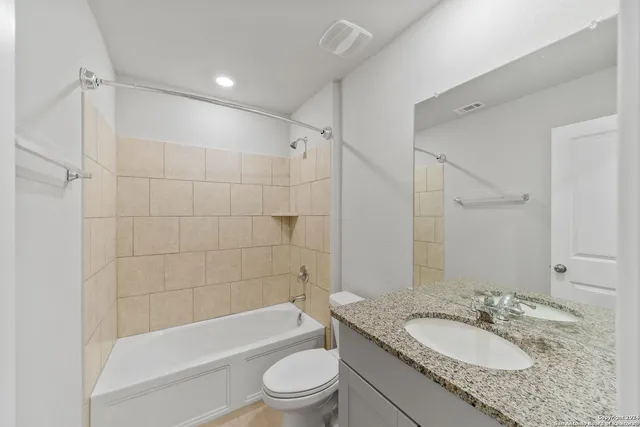 a bathroom with a granite countertop sink toilet mirror and bathtub