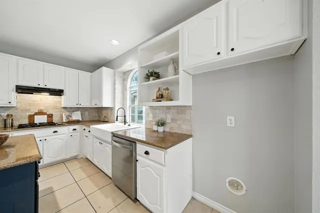 a kitchen with a sink dishwasher stove and white cabinets