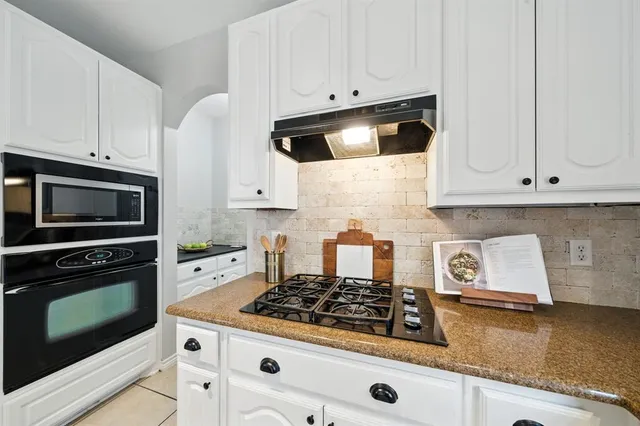 a kitchen with granite countertop white cabinets and stainless steel appliances