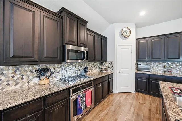 a kitchen with stainless steel appliances granite countertop a table chairs sink refrigerator and cabinets