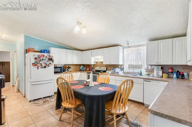 a kitchen with stainless steel appliances kitchen island granite countertop a dining table chairs and refrigerator