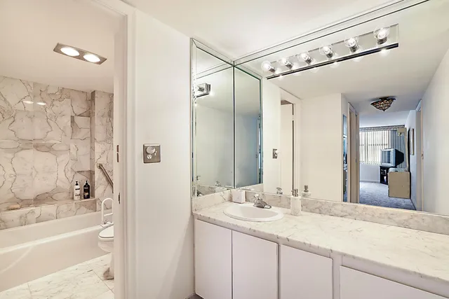 a bathroom with a sink granite countertop toilet a mirror and shower