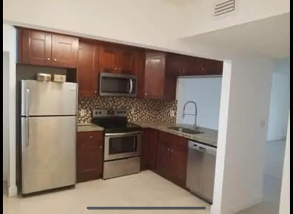 a kitchen with stainless steel appliances granite countertop a refrigerator a stove a sink and a microwave