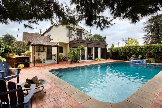 a view of swimming pool with lawn chairs and plants