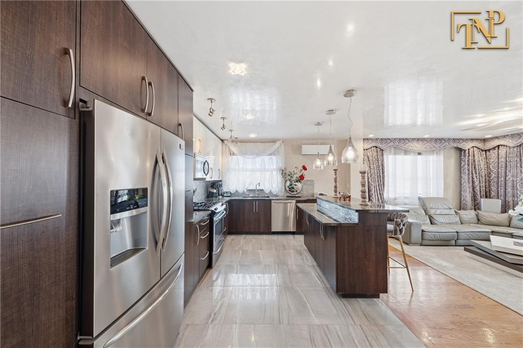 2854 Brighton 4th Street, Unit 6 Brooklyn, NY 11235 - Photo 4 of 19 a kitchen with stainless steel appliances a refrigerator a stove a sink dishwasher and a dining table with wooden floor
